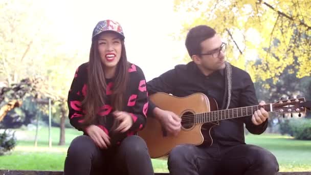 男がギターを弾きながら歌っている女性 — ストック動画