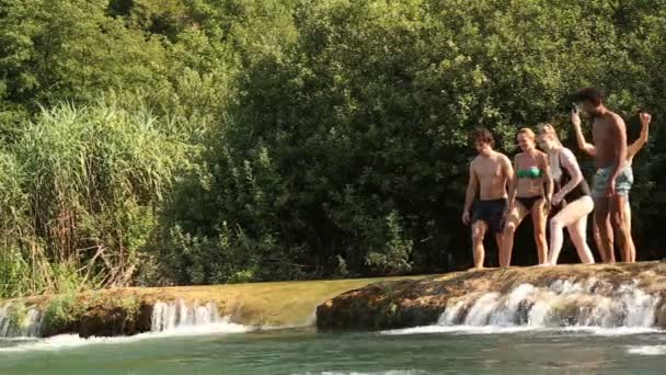 Мужчина прыгает в реку с друзьями — стоковое видео