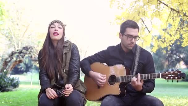 Женщина поет, пока мужчина играет на гитаре — стоковое видео