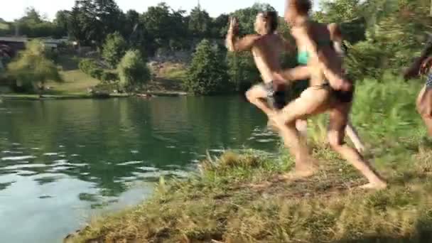 Друзья бегут и прыгают в реку — стоковое видео