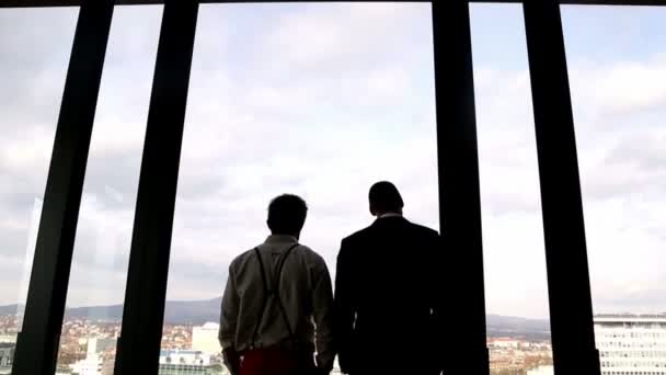 Empresários olhando para a cidade através da janela — Vídeo de Stock