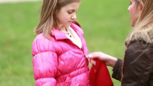 Мать застегивает куртку дочери — стоковое видео