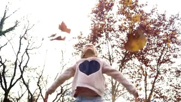 Meisje bladeren gooien in de lucht — Stockvideo