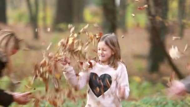 Chica lanzando hojas en sus padres — Vídeo de stock