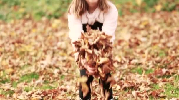 fille jeter des feuilles dans le parc 