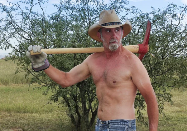 A Shirtless Cowboy Shoulders a Red Pickax — Stock Photo, Image