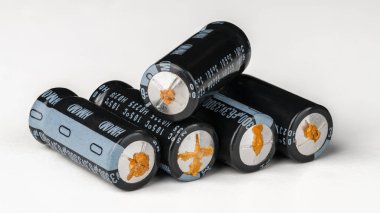 Alüminyum elektrolitik kondansatörler beyaz arka planda kullanılmadığından arızalı. Sızdıran elektrolit sıvısı olan kondansatör yığını. Pasif elektronik bileşenler hasar görmüş. E-atık. Yan görünüm.