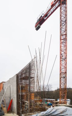 Destekli beton istinat duvarı inşaatı. Kule vinci ve ferrobeton takviyeli çelik parmaklıklar. İnşaat alanında paslı demir teller var. İnşaat mühendisliği.