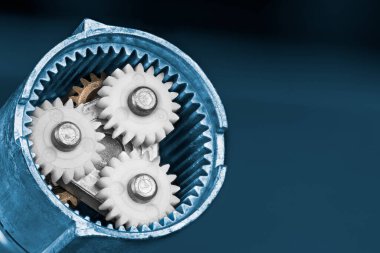 Beyaz gezegen, mavi arka planda destansı dişli bir çarkın içinde. Parçalanmış elektrikli vida tabancası vites kutusunda plastik ve metal dişli tekerleklere yakın çekim. Makine mühendisliği.