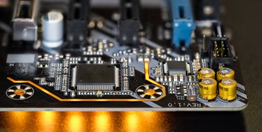 Elektronik bileşenli modern bilgisayar anakart detaylarına basılı devre kartı. Mikro çipler, kondansatörler veya rezistanslar ve siyah zemin üzerinde sarı LED ışık efektleri. Yüzey montaj teknolojisi.