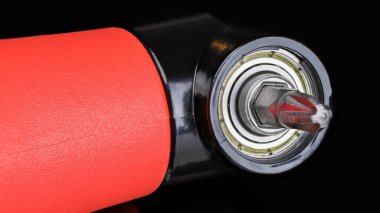 Cruciform tornavida parçası, siyah bir arkaplanda, dik açı adaptörüyle tutturulmuş. Cross Pozidriv tipi vida sürücüsü metal kafası ve kırmızı plastik saplı elektrikli el aleti..
