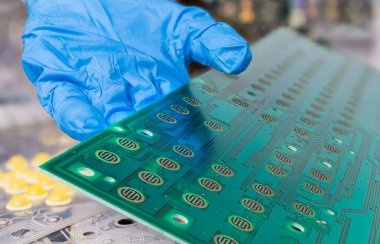 Sökülmüş bilgisayar klavyesinin basılı devre kartı mavi eldivenle insan elinin detaylarına işlenmiş. Yeşil elektronik PCB 'yi elinde tutan tamirci. Düğme düğmeleri ve bakır katman üzerinde çizgi deseni var. E-atık sıralama.