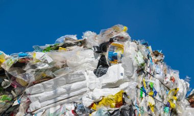 Boş tek kullanımlık plastik ambalajların ayrıntıları mavi gökyüzü arka planında sıkıştı. Geri dönüşüm için atık ayırma. Poşet, çuval ya da kutu olarak kullanılan paketler ve beyaz genişletilmiş polistiren. Çöp yığını..