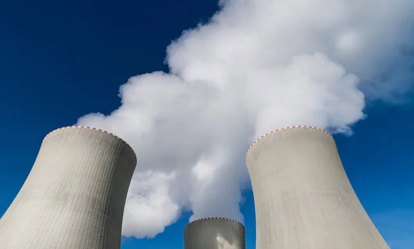 Nükleer enerji santralinin kapatılması soğutma kuleleri beyaz su buharı püskürtüyor. Büyük beton yapıların en üst ayrıntıları mavi gökyüzü arka planındaki modern üretim istasyonundan ısıyı kaldırıyor. Eko.