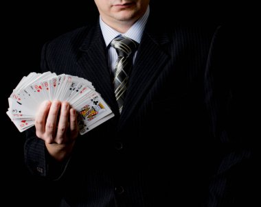 Siyah takım elbiseli ve kravatlı bir adam elinde siyah arka planlı 4 as tutuyor. Poker kartları. Poker ve kumar oynayın. Kumar siteleri, makaleler, reklamlar, hediyeler için kullan.