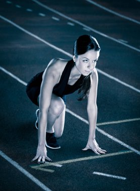 Güzel bayan koşucu pistte başlamayı bekliyor.