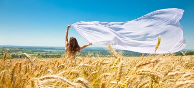 Buğday tarlasında kumaşlı mutlu genç bir kadın. Yaz seti