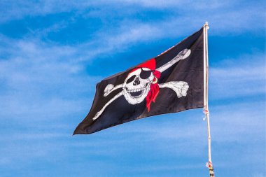 PUKET, THAILAND-FEB 2, 2016: Jolly Roger Black korsan bayrağı 2 Şubat 2016 tarihinde Phuket, Tayland 'da mavi gökyüzünde insan kafatası ile.