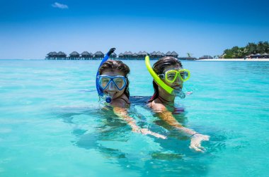 Maldivler 'deki Olhuveli adasında topikal plajda dalış maskeli iki mutlu kız..