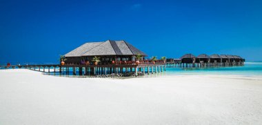 Olhuveli Adası, Maldivler 'de dinlenmek için wihte plajı ve turkuaz suyu olan güzel bir tropikal tatil köyü. Mercan resifli beyaz kumsal. Rahatlamak, güneşlenmek ve şnorkelle yüzmek için en iyi plaj..