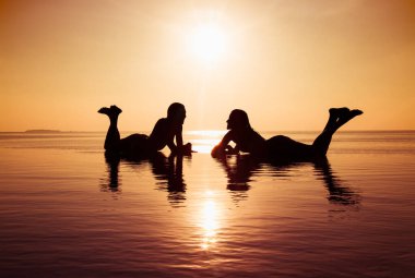 İki güzel kız sonsuz havuzda eğleniyor. Maldivler.