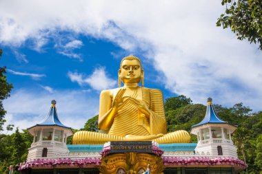 The giant golden Buddha statue sitting on the roof of the Golden Temple in Dambulla Sri Lanka. Built in 2001 it is said to be the largest of its kind in the world. clipart