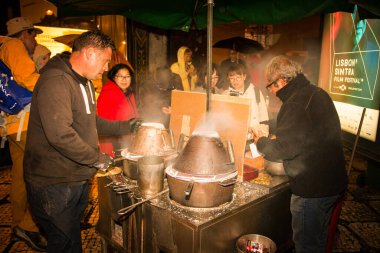 LISBON PORTUGAL - 30 Ekim 2018: Lizbon Portekiz sokaklarında turistlere kavrulmuş kestane satan iki adam.