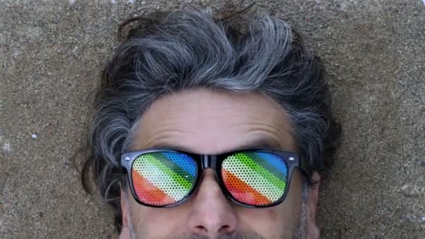 Homme aux cheveux gris posé sur une plage de sable — Video