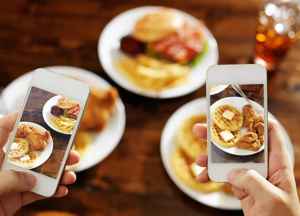 Двое друзей фотографируют еду со смартфонами — стоковое фото