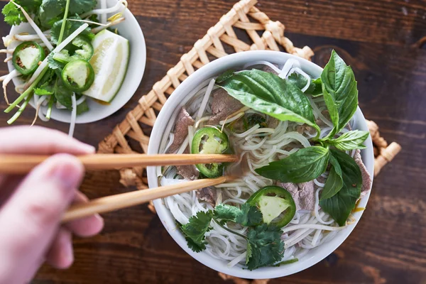 Pho vietnamita con carne de res comido con palillos — Foto de Stock