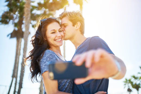 Man kissing his girlfriend on the cheek — Stock Photo, Image