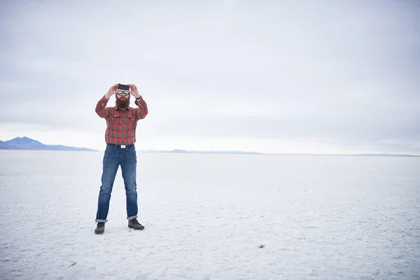 Hipster solitário com barba incrível usando telefone inteligente em apartamentos de sal desolados — Fotografia de Stock