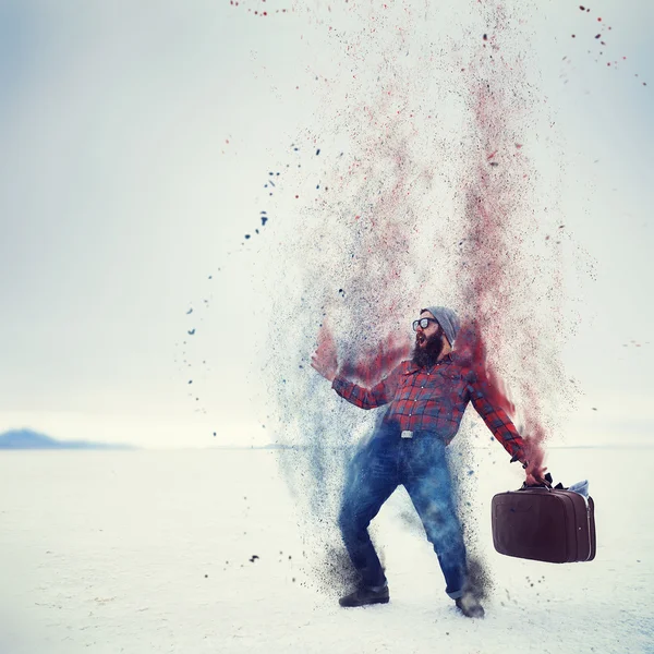hipster with beard and suitcase turning into dust on the salt flats