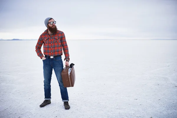 Totalmente despreocupado solitario viajero hipster de pie con maleta retro en grandes pisos de sal vacíos —  Fotos de Stock