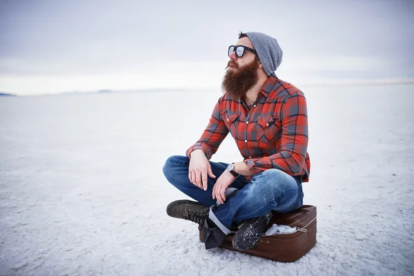 Hipster barbudo sozinho nos apartamentos de sal olhando para fora em pensamento profundo — Fotografia de Stock