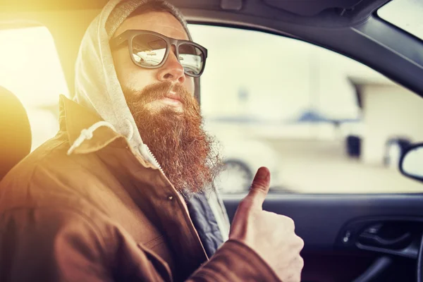 Hipster with beard sitting in car giving thumbs up — Stock Photo, Image