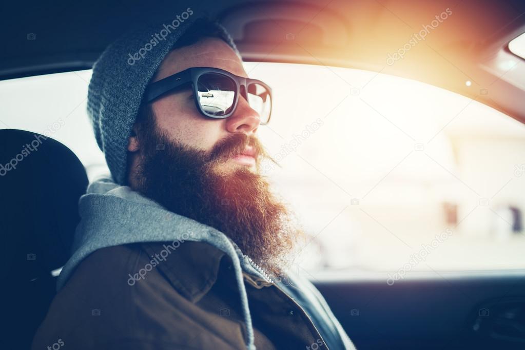 bearded hipster wearing sunglasses inside car