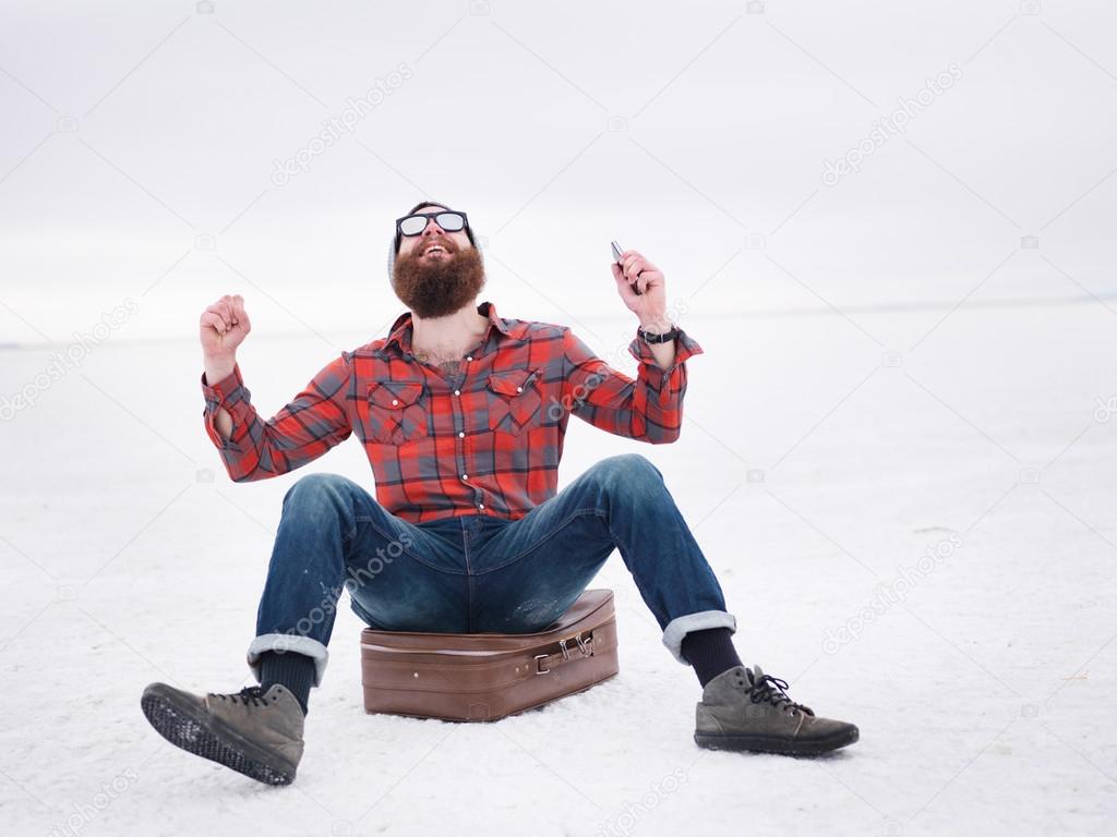 lost hipster on the salt flats sitting on suit case finds what he is looking for