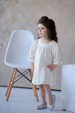 Arkaplanda poz veren mütevazı bir kızın portresi. Güzellik, çocuklar için moda. Küçük şirin bir kız pozu..