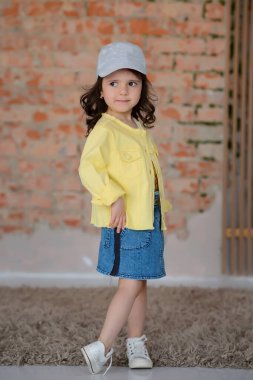 Arkaplanda poz veren mütevazı bir kızın portresi. Güzellik, çocuklar için moda. Küçük şirin bir kız pozu..