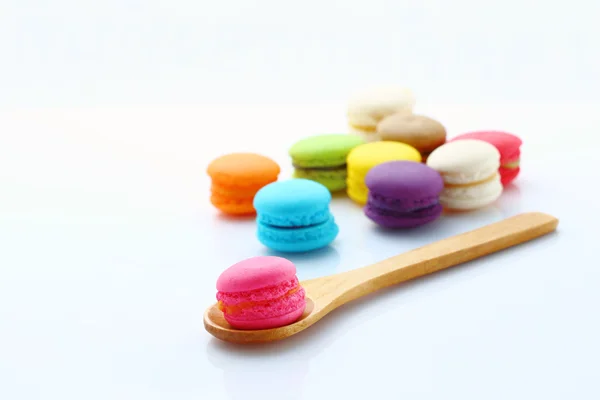 Macarons coloridos con cuchara de madera en blanco . — Foto de Stock