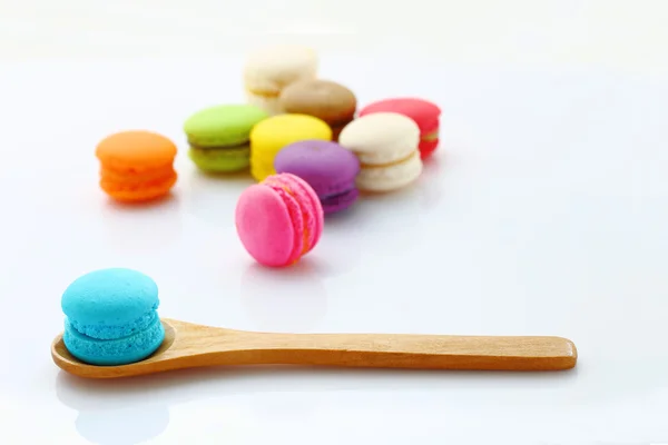 Macarons coloridos con cuchara de madera en blanco . — Foto de Stock