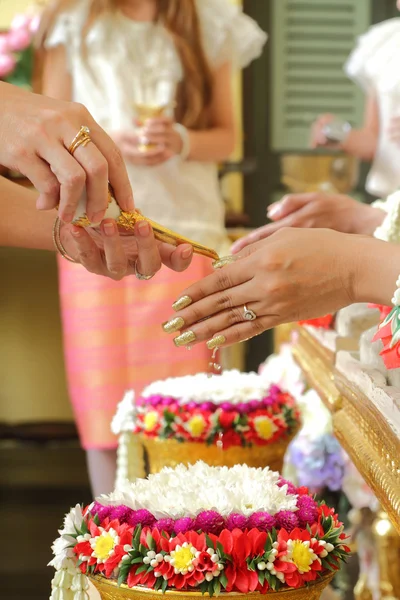 Hände gießen Segenswasser in die Hände der Braut, thailändische Hochzeit. — Stockfoto