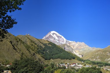 Gergeti village, Georgia yakınındaki Mount Kazbek ve Holy Trinity Kilisesi (Tsminda Sameba) görünümü