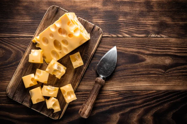 Нарезанный сыр на деревенском деревянном столе — стоковое фото