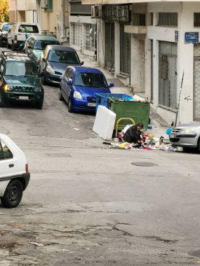 Atina, Yunanistan - 2 Şubat 2020: Yaşlı bir adam çöp tenekesinde bir şeyler arıyor.