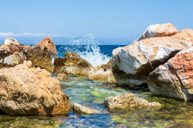 The waves breaking on a stony beach, forming a spray. Greece.