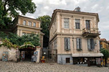 Filibe, Bulgaristan - 7 Ağustos 2025: Bulgaristan 'ın Plovdiv kentinde hediyelik eşya dükkanları olan eski binalar, yıpranmış cepheler, pencereler ve kaldırımlı caddeler yer alıyor.