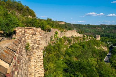 Bulgaristan 'ın Veliko Tarnovo kentindeki orman yamacı boyunca uzanan Çarevets Kalesi' nin uzun ortaçağ taş duvarlarının panoramik manzarası.