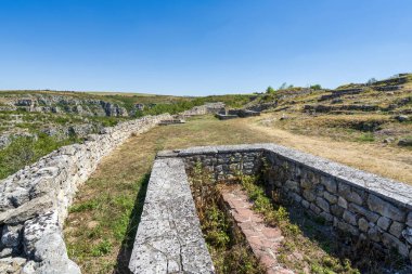 Bulgaristan 'daki ortaçağ Cherven Kalesi' nin antik taş kalıntıları ve savunma duvarları derin bir nehir geçidine tünemiş ve engebeli uçurumlar ve yaz bitkileriyle çevrili..